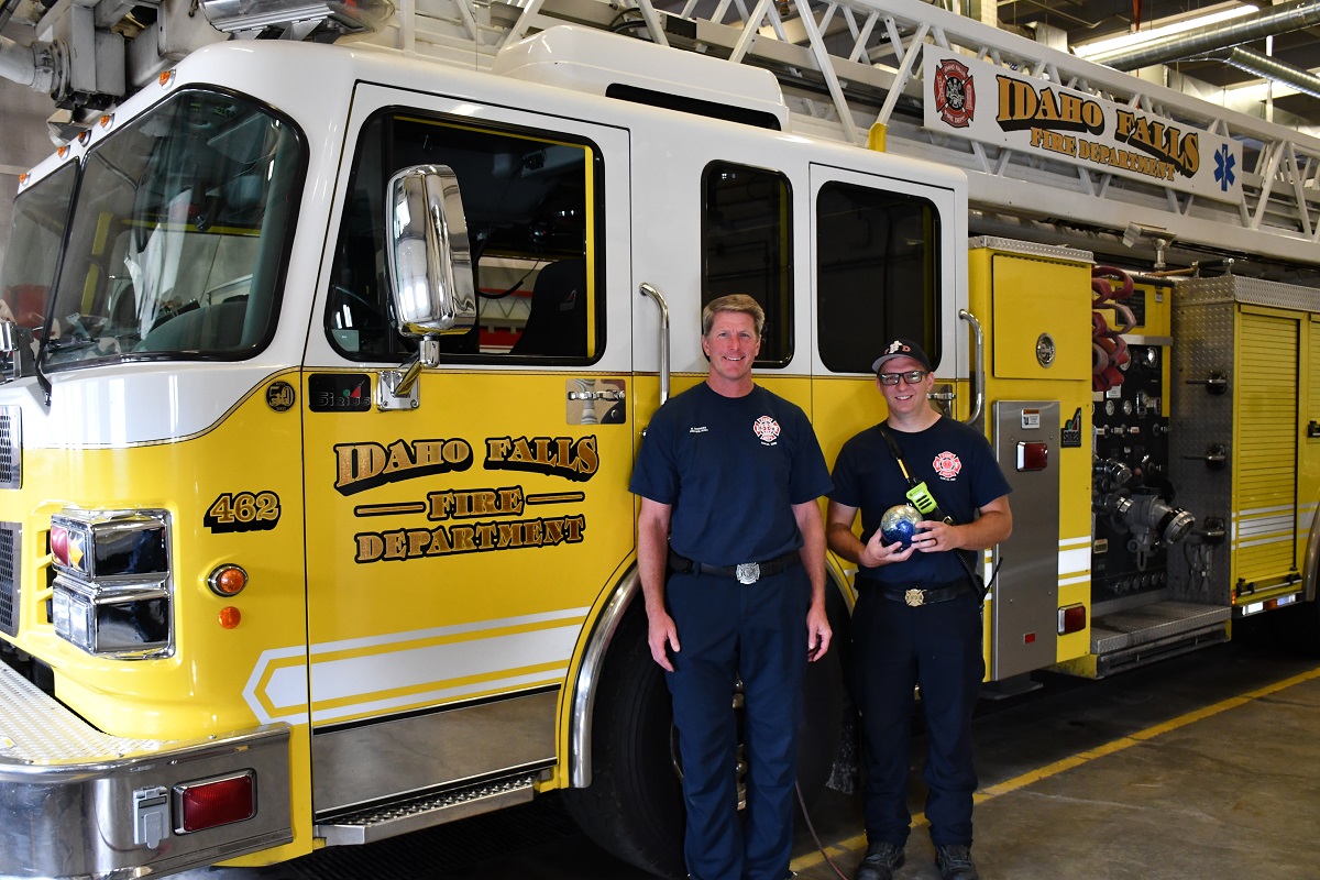 a couple of men standing in front of a fire truck